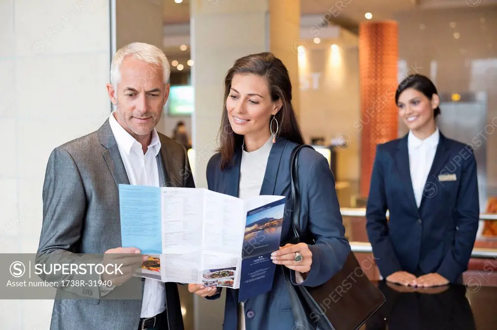 Business couple reading a brochure in front of a hotel reception counter