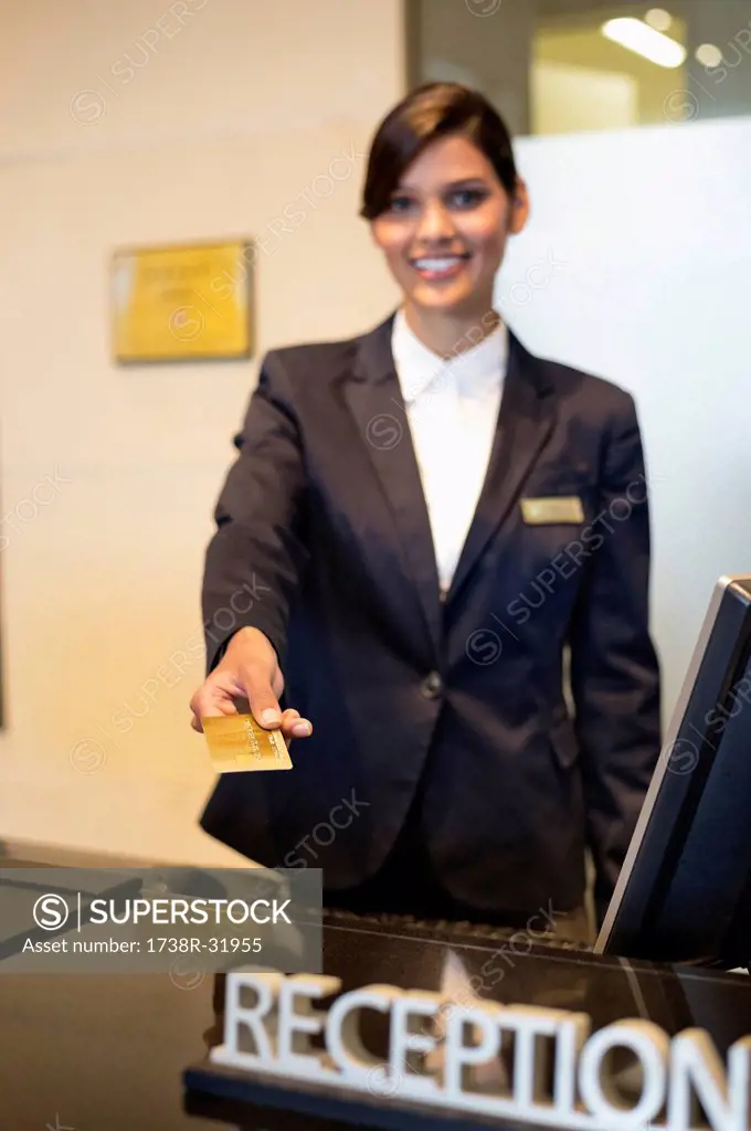 Receptionist holding a credit card and smiling at the hotel reception counter
