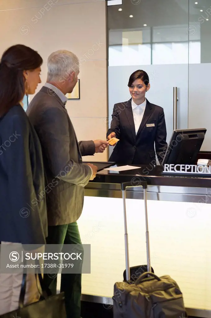 Business couple paying with a credit card at the hotel reception counter
