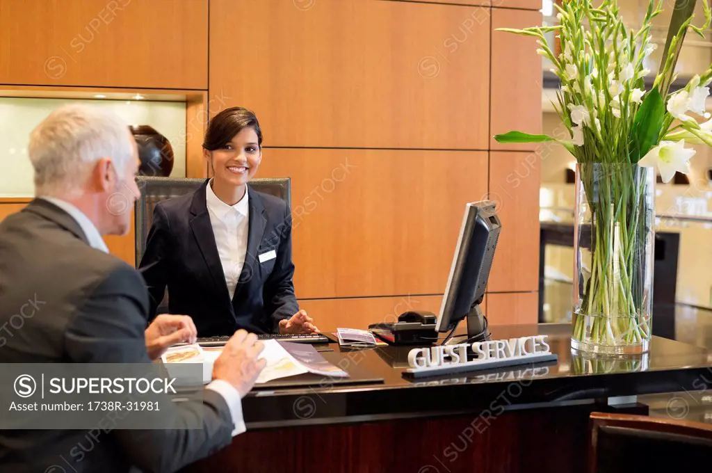 Businessman talking with a receptionist at the hotel reception counter