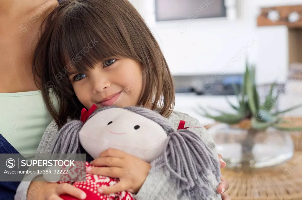 Close-up of a girl sitting with her mother and holding a rag doll