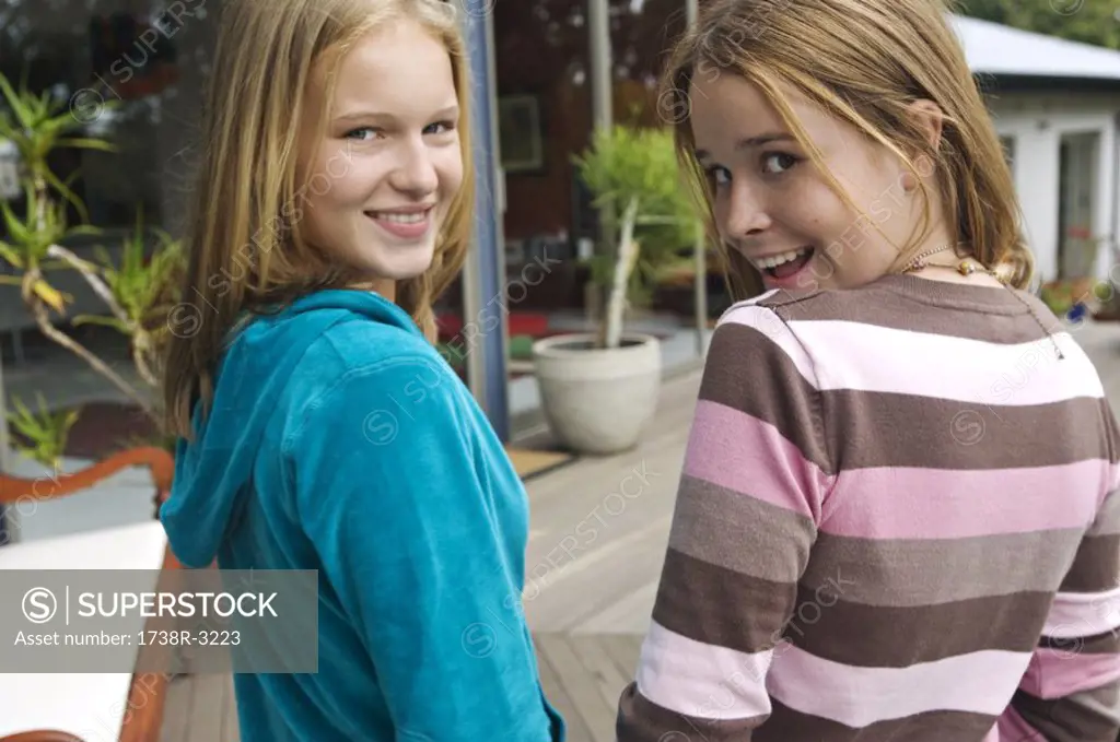 2 smiling teenage girls looking over shoulders