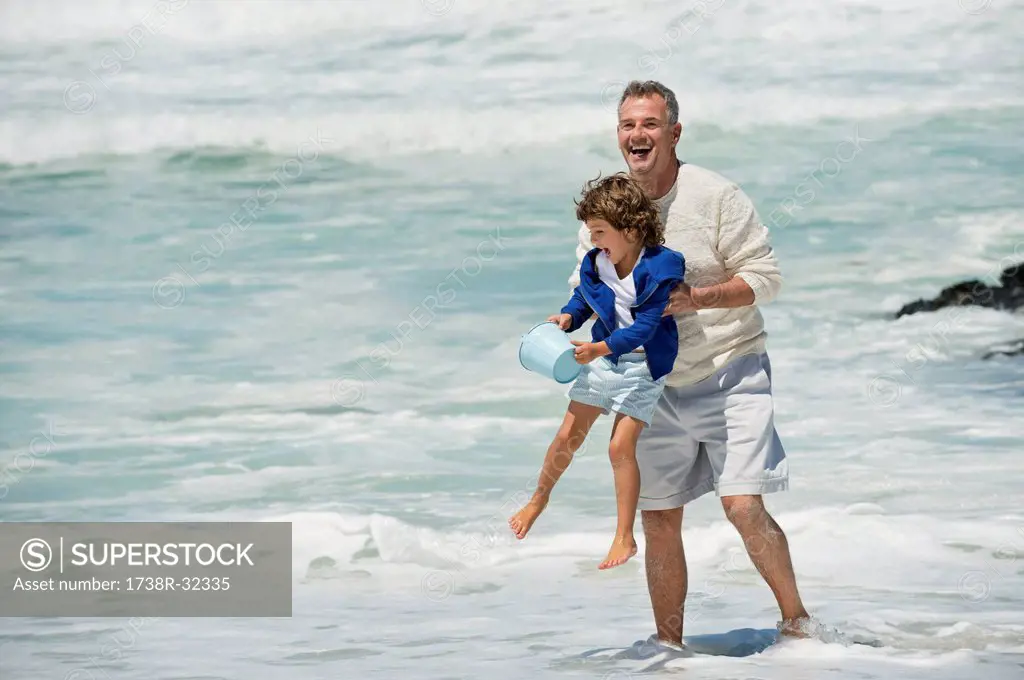 Boy playing with his grandfather on the beach