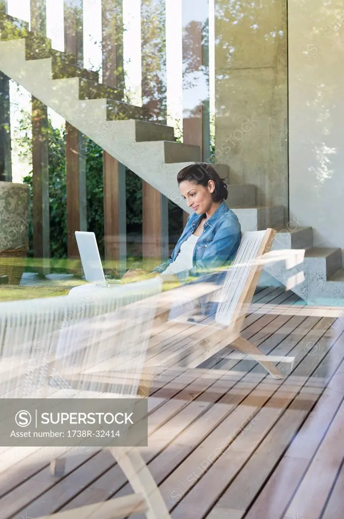 Woman using a laptop viewed through from a glass wall