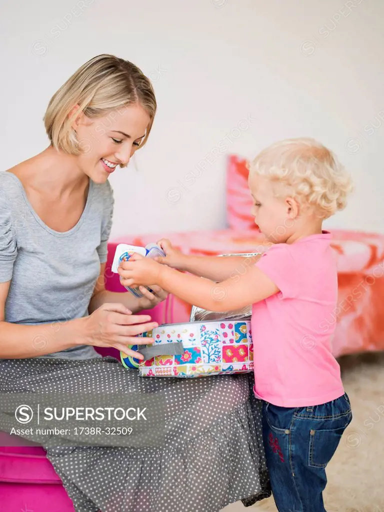 Smiling woman opening a box for her daughter