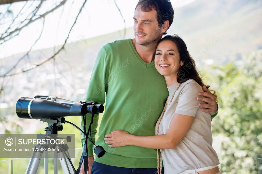 Couple smiling beside a binoculars on tripod