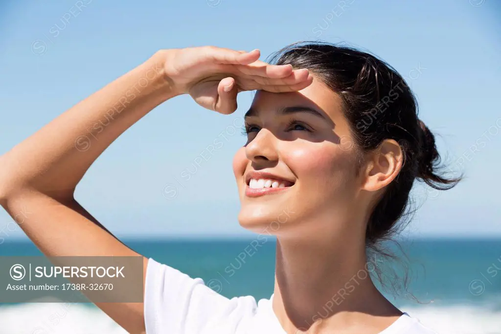 Beautiful woman shielding eyes on the beach