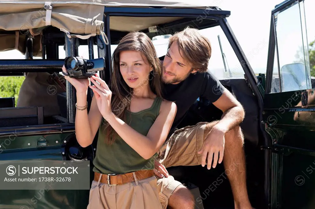 Woman filming with a video camera with her boyfriend on SUV