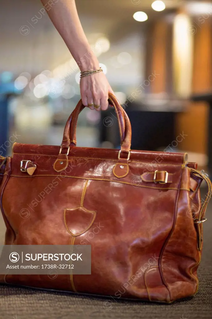 Close-up of a woman's hand picking up a leather purse