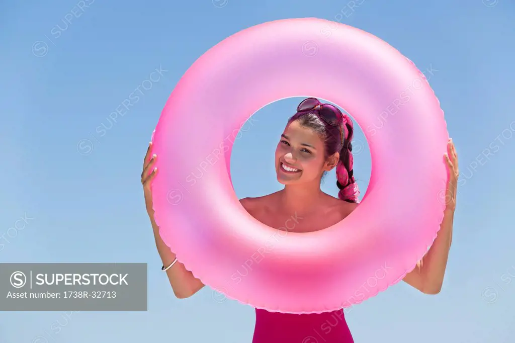 Beautiful woman looking through an inflatable ring on the beach