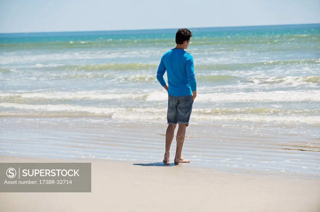 Man standing on the beach and looking at the sea