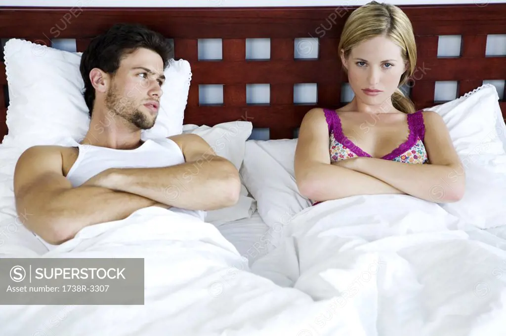 Young couple in bed, arms crossed