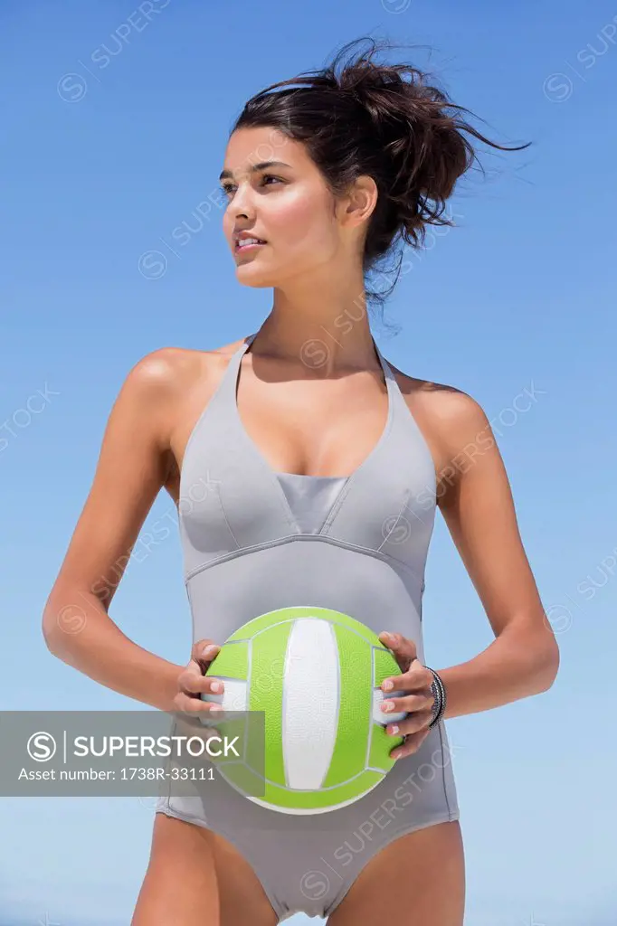 Beautiful woman holding a volleyball on the beach