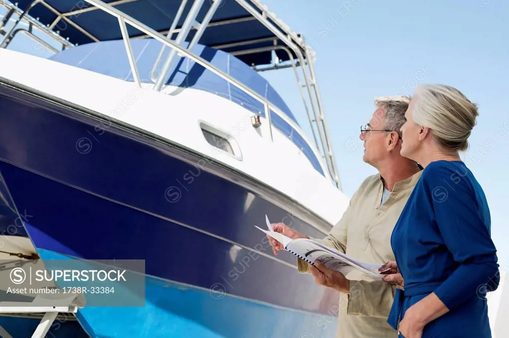 Couple standing near a yacht with a brochure