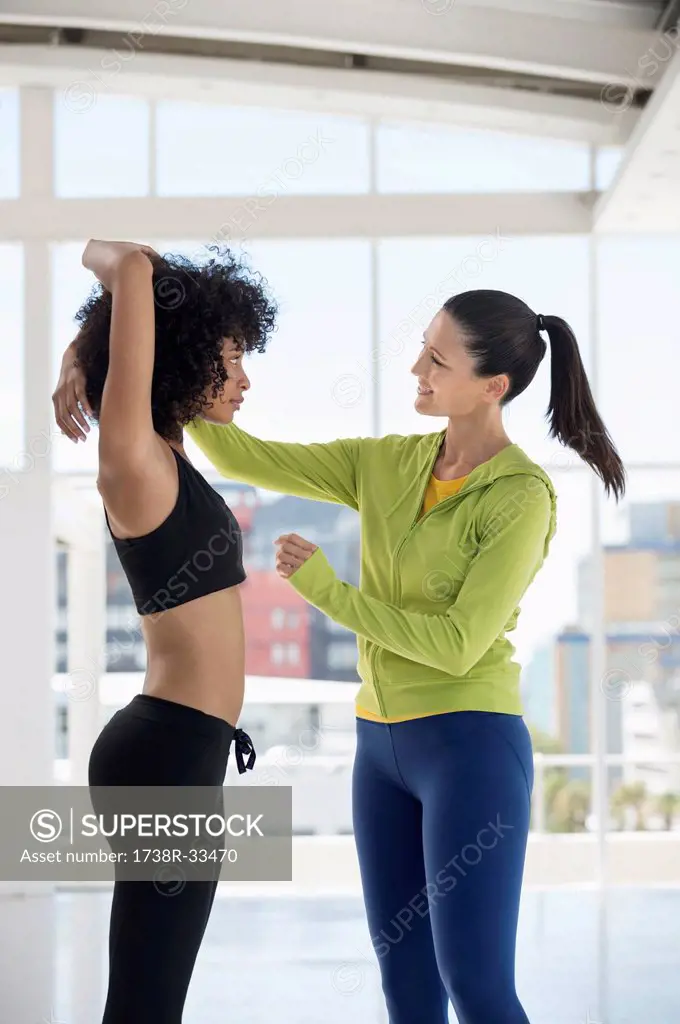 Female instructor assisting a woman in a gym