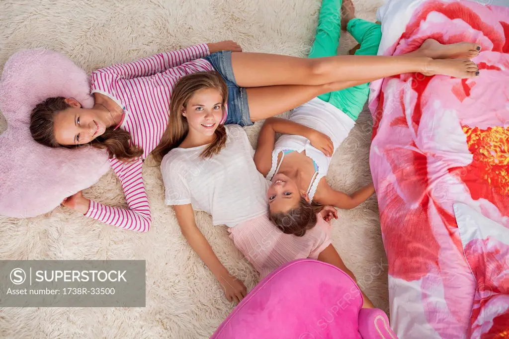Three girls lying on a carpet at a slumber party