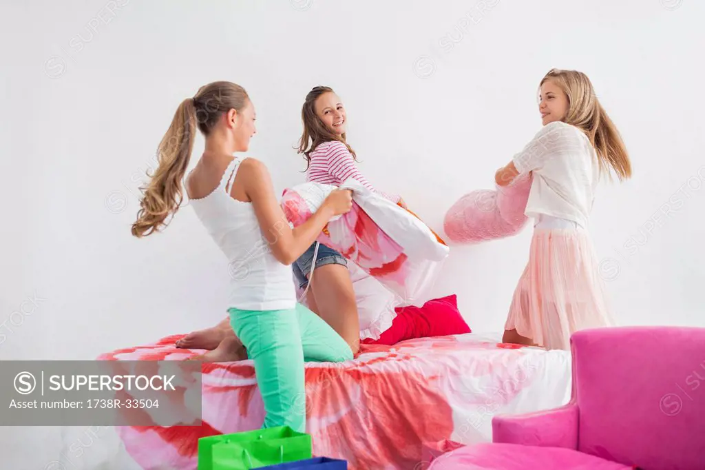 Girls having pillow fight on the bed at a slumber party