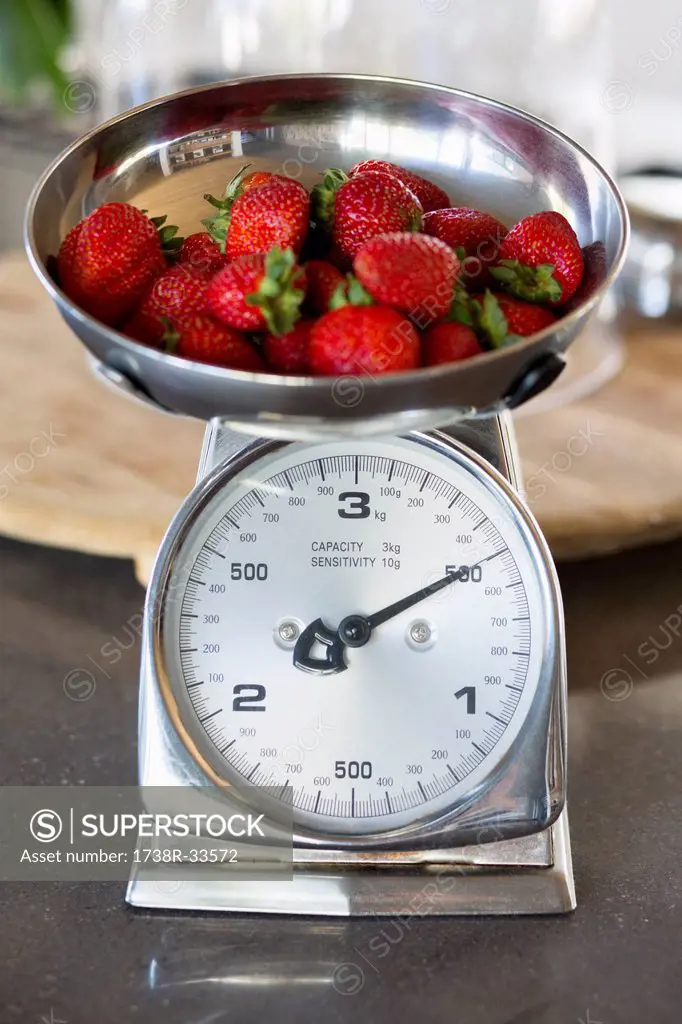 Strawberries on a weighing scale at a kitchen counter