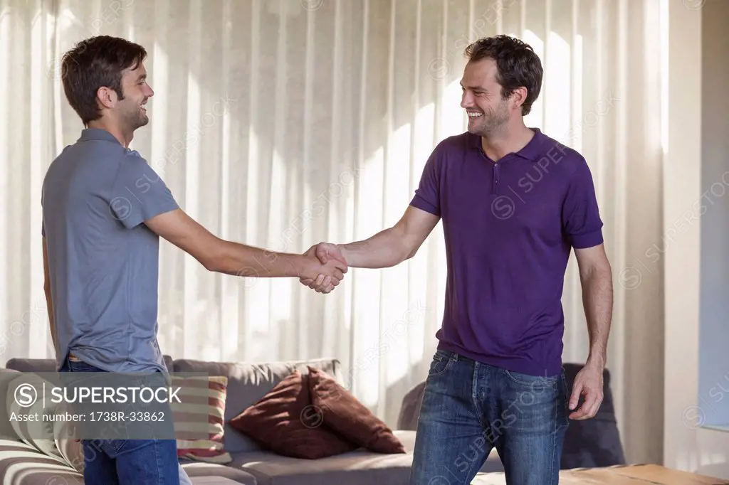 Two friends shaking hands and smiling