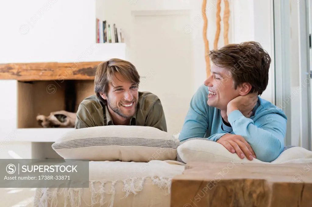 Two male friends smiling on the bed