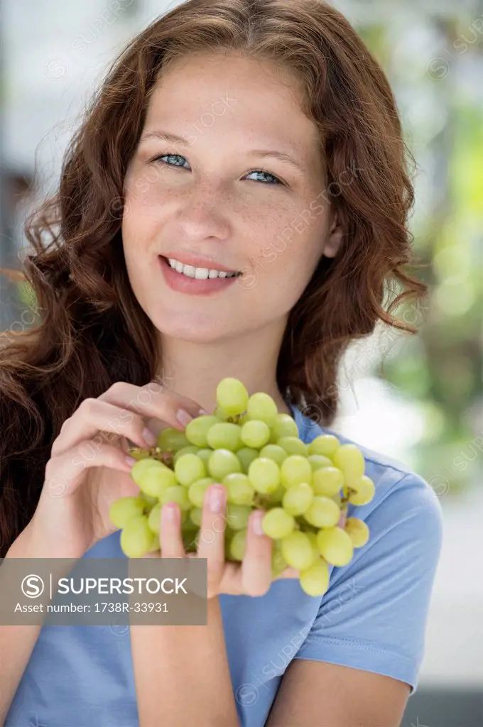 Portrait of a woman eating grapes