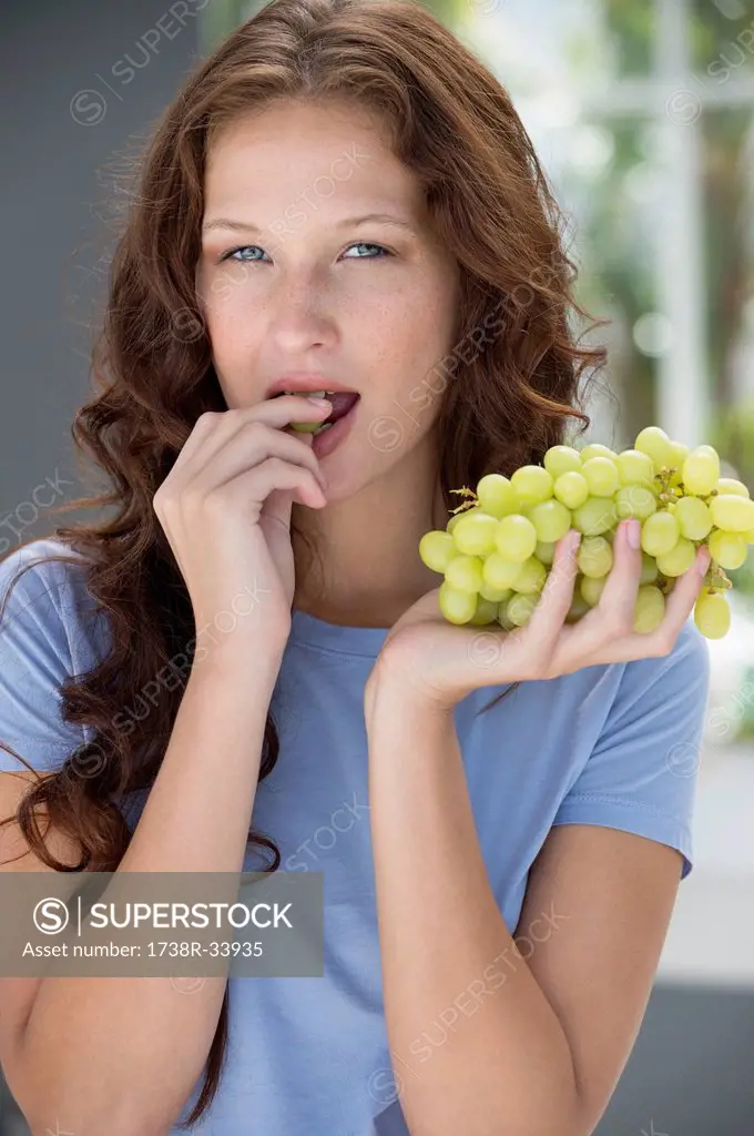 Portrait of a woman eating grapes