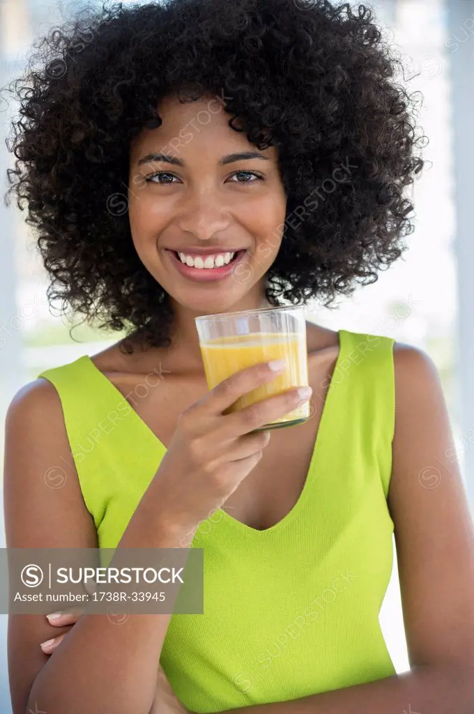 Portrait of a smiling woman holding a glass of mango shake