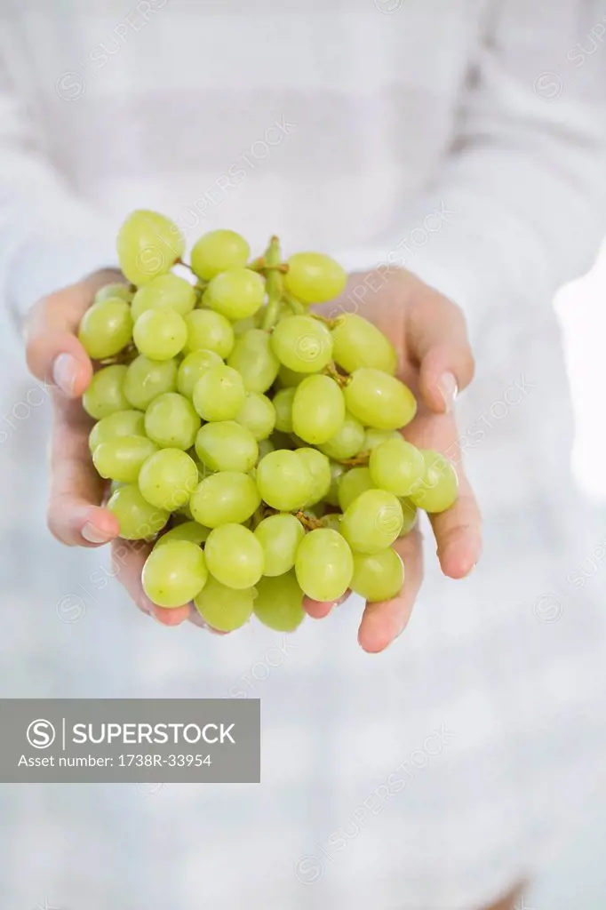 Close-up of a woman's hand holding bunch of grapes