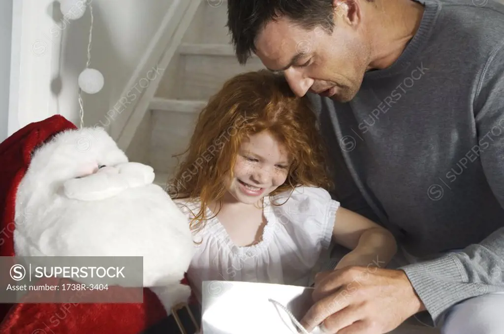 Father and ldaughter opening Christmas presents, indoors