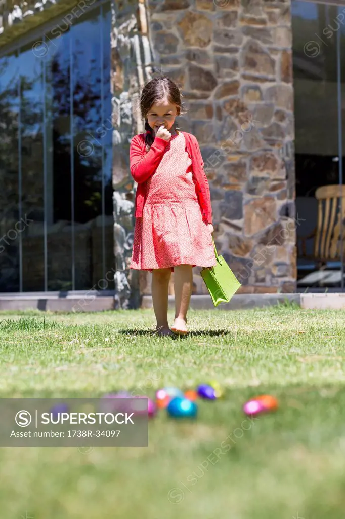 Girl looking at Easter eggs in a lawn