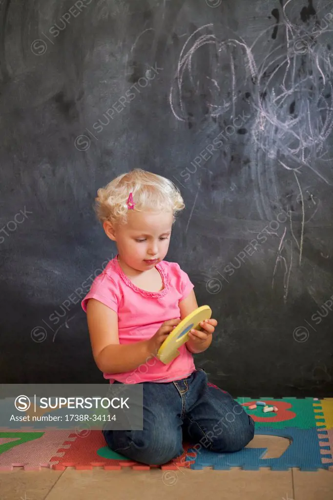 Girl playing with number puzzle in front of a black board