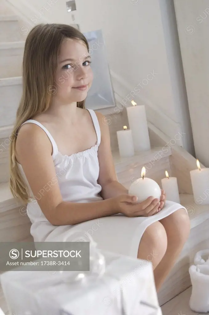 Christmas, little girl sitting indoors, holding a candle, indoors