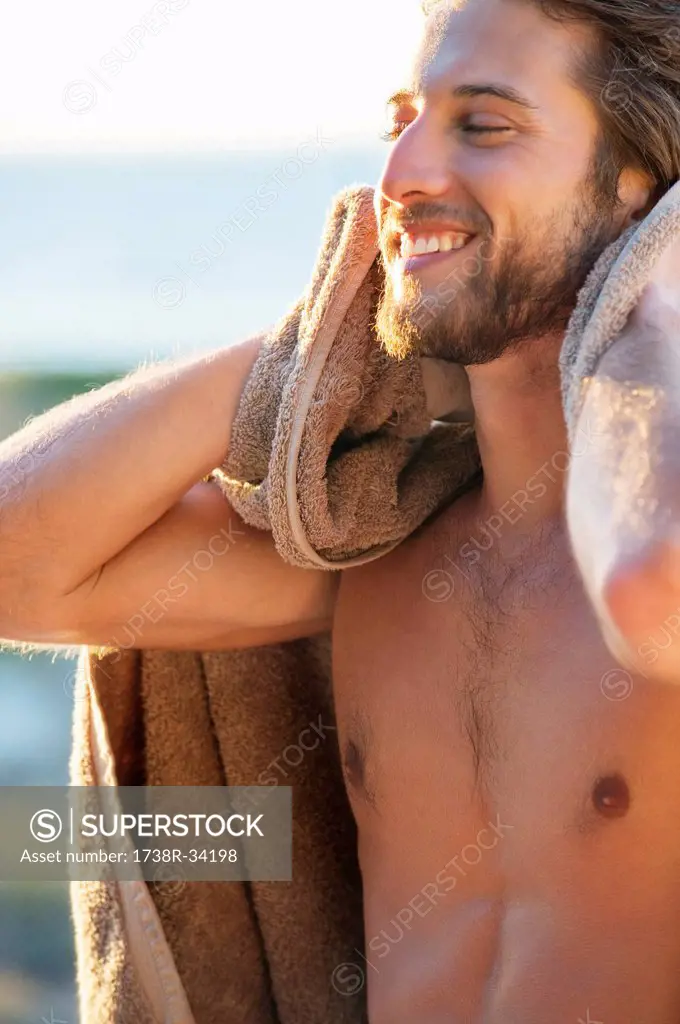 Happy man wiping himself with a towel on the beach