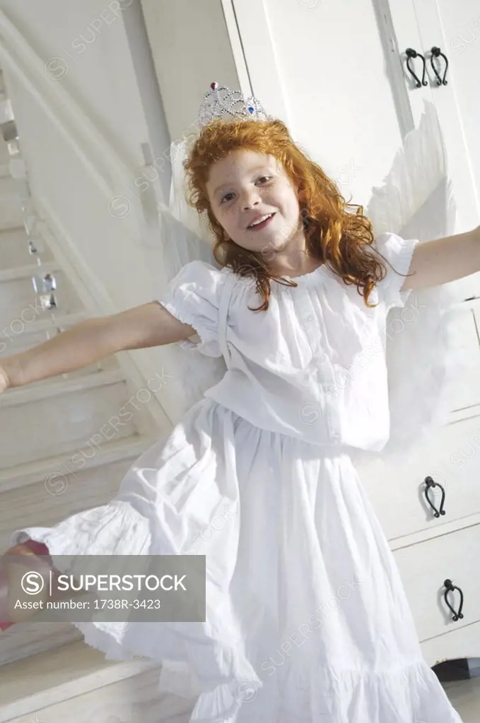 Little girl in an angel costume, looking at the camera, indoors