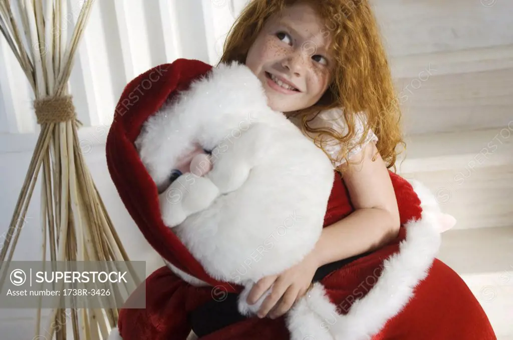 Christmas day, portrait of a little girl holding a cuddly toy Santa Claus, indoors