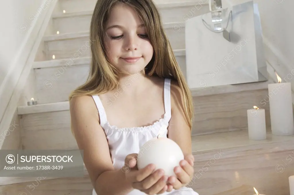 Christmas, little girl sitting indoors, holding a candle, indoors