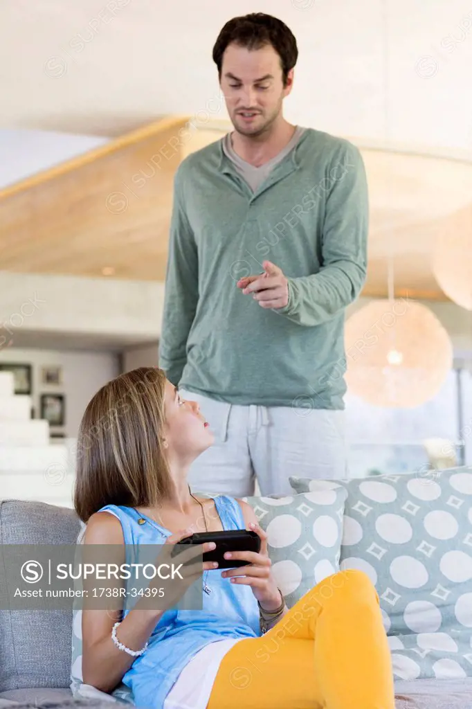 Man scolding his daughter for playing video game