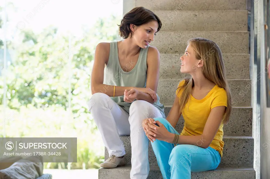 Mother and daughter sitting on steps and talking to each other