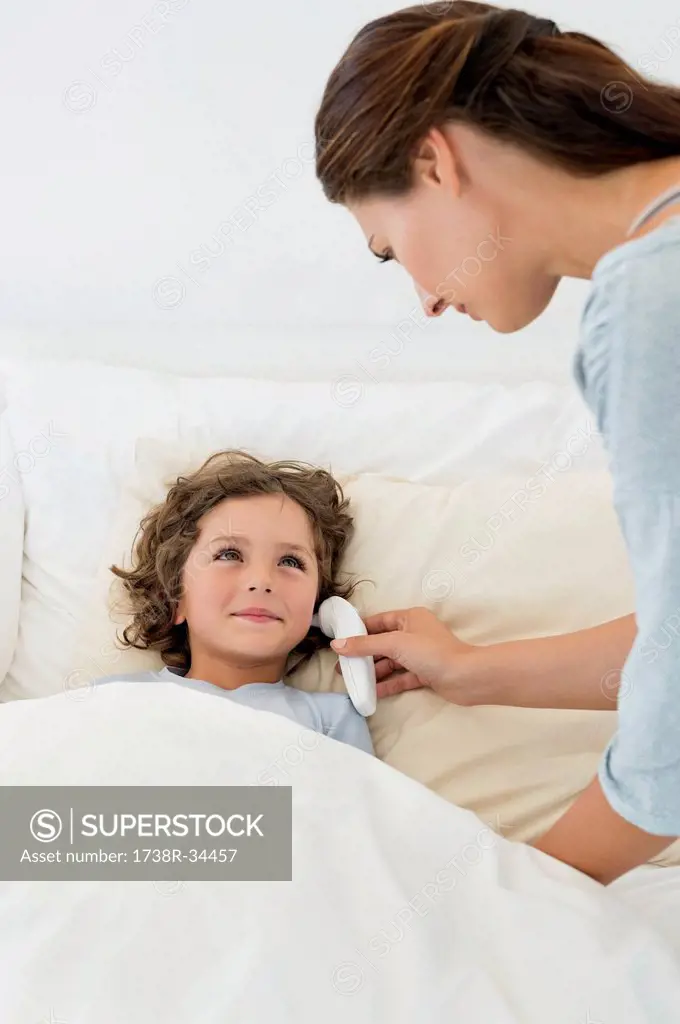 Woman checking fever of her son with a thermometer