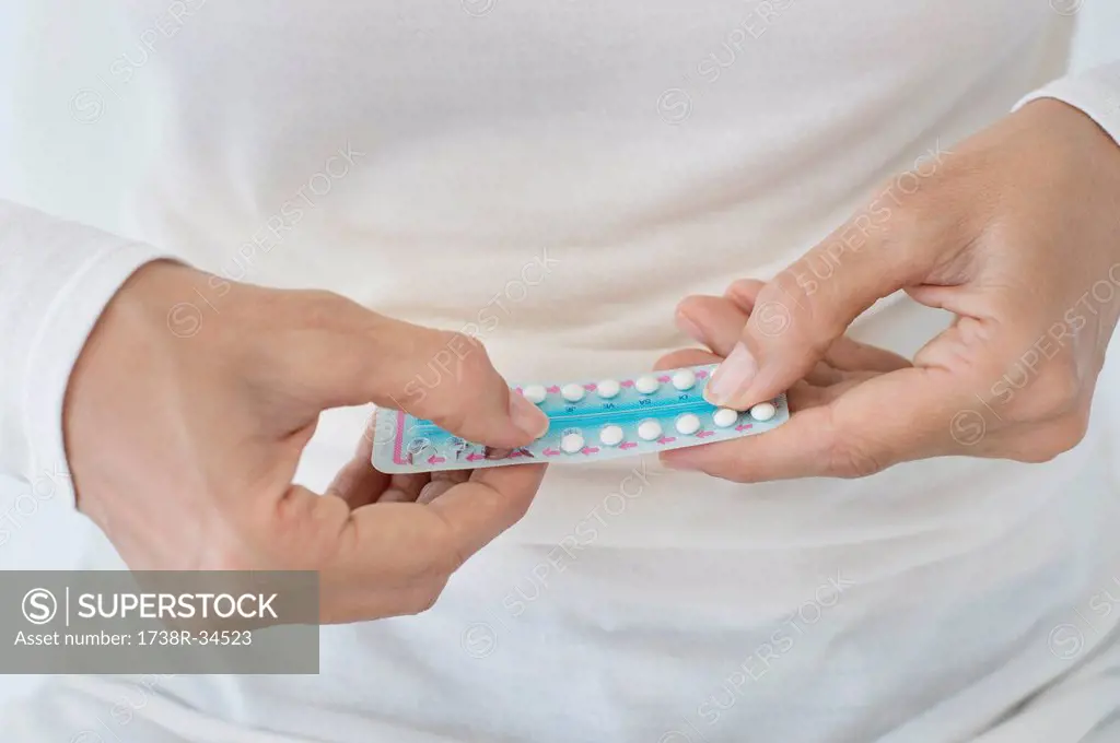 Mid section view of a woman holding a blister pack of contraceptive pills