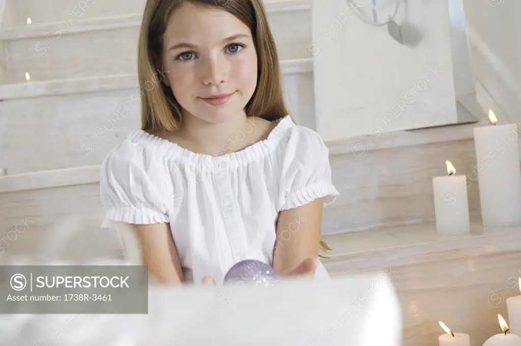 Little girl sitting indoors, holding a Christmas ball