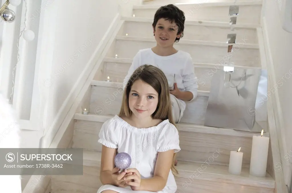 Little girl sitting indoors, holding a Christmas ball