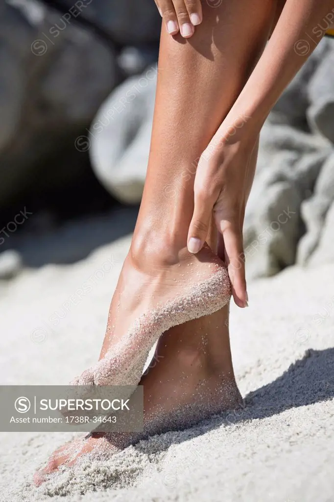 Woman cleaning sand of her feet