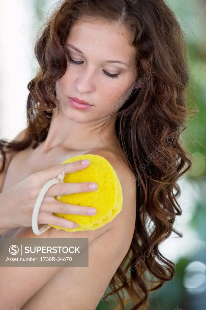Woman cleaning her body with bath sponge
