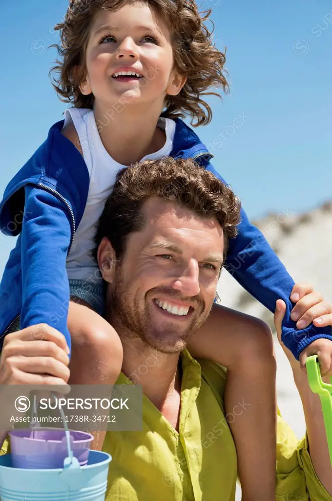 Man carrying his son on shoulders on the beach