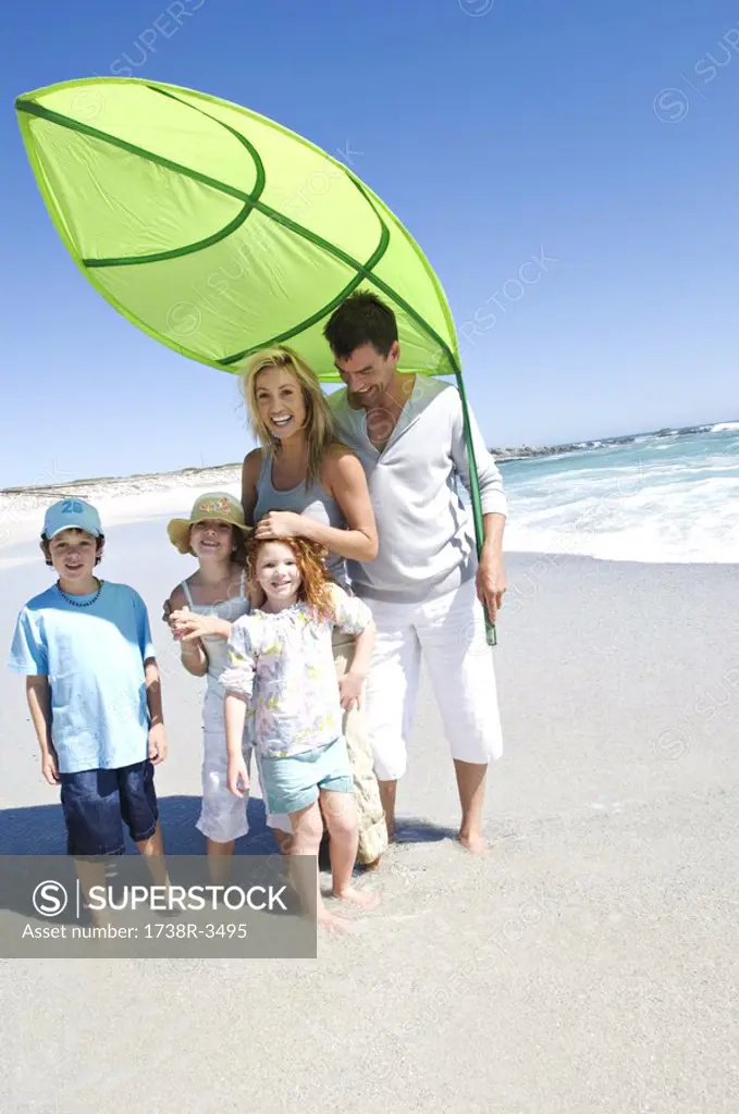 Parents and three children on the beach posing for the camera, outdoors