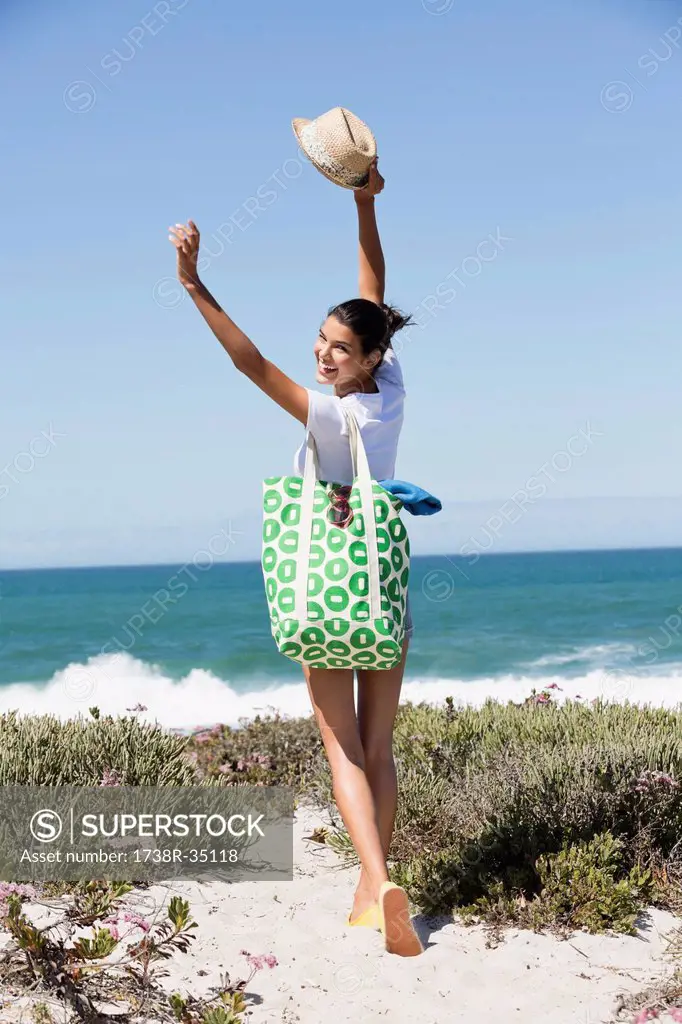 Happy woman carrying a bag on the beach