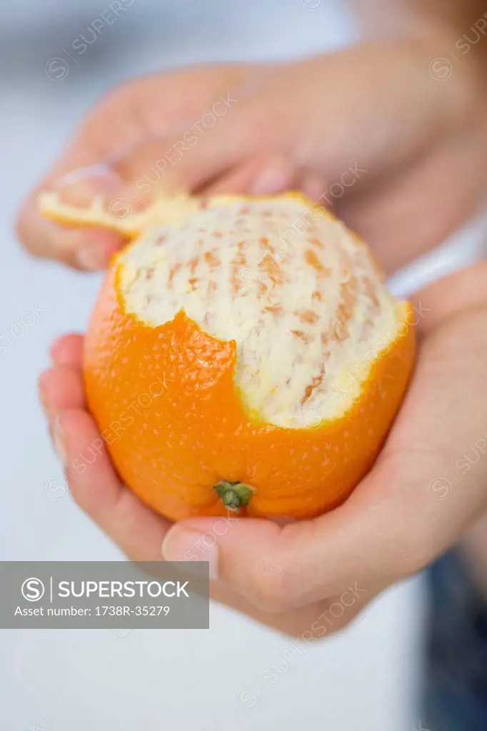 Close-up of a woman's hand peeling an orange