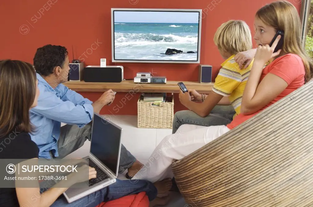 Parents and two teenagers watching television, indoors