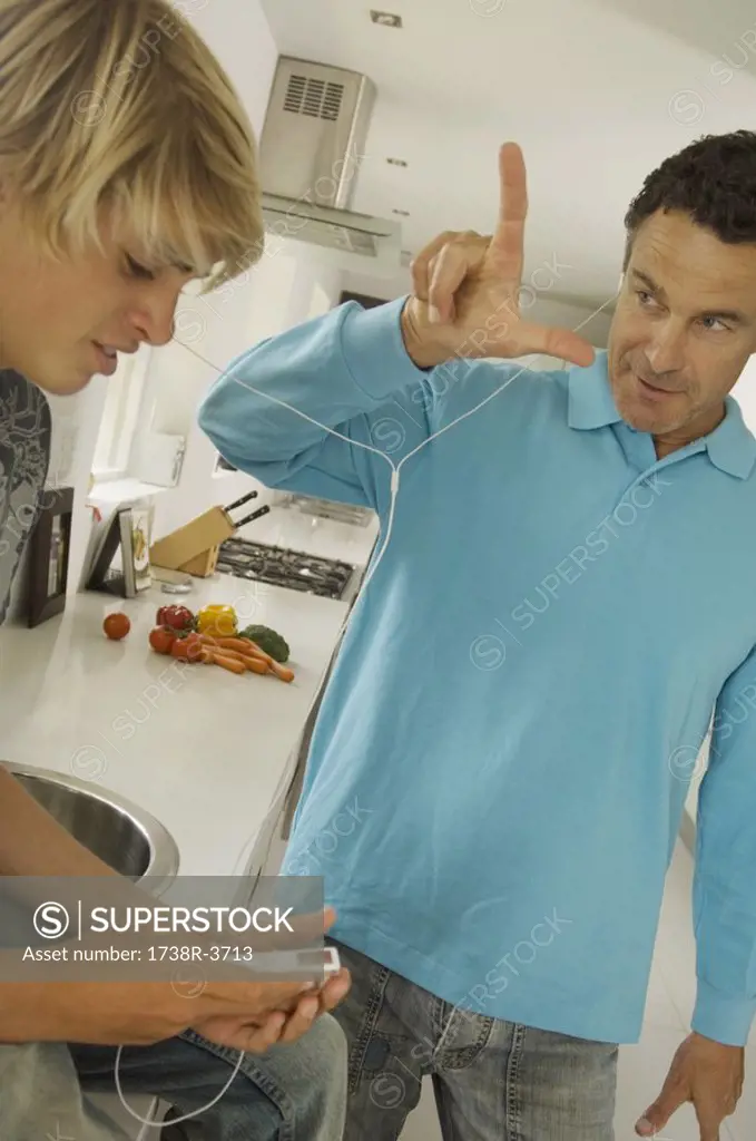 Father and teenager listening to MP3 player, indoors